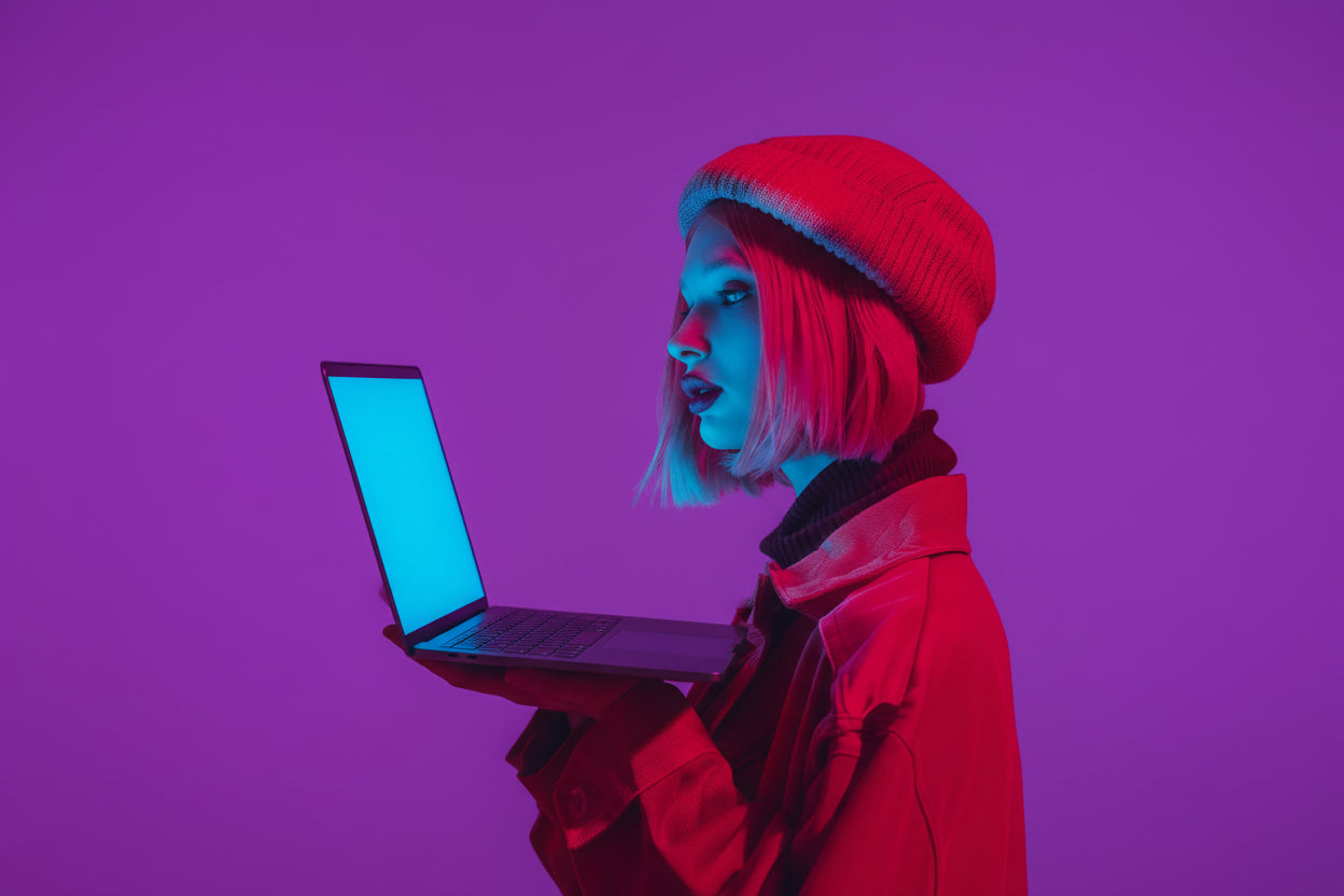 Person wearing a red outfit and hat holding a glowing blue laptop on a purple background